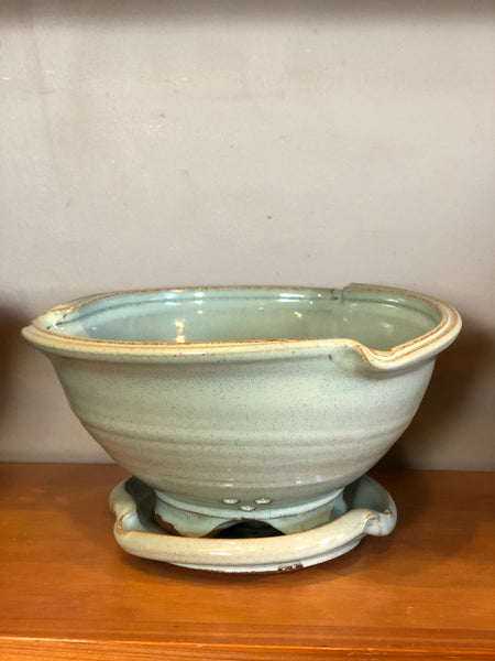 Strainer-style bowl with decorative rim treatment, and sitting on a tray with a similar decorative rim treatment.